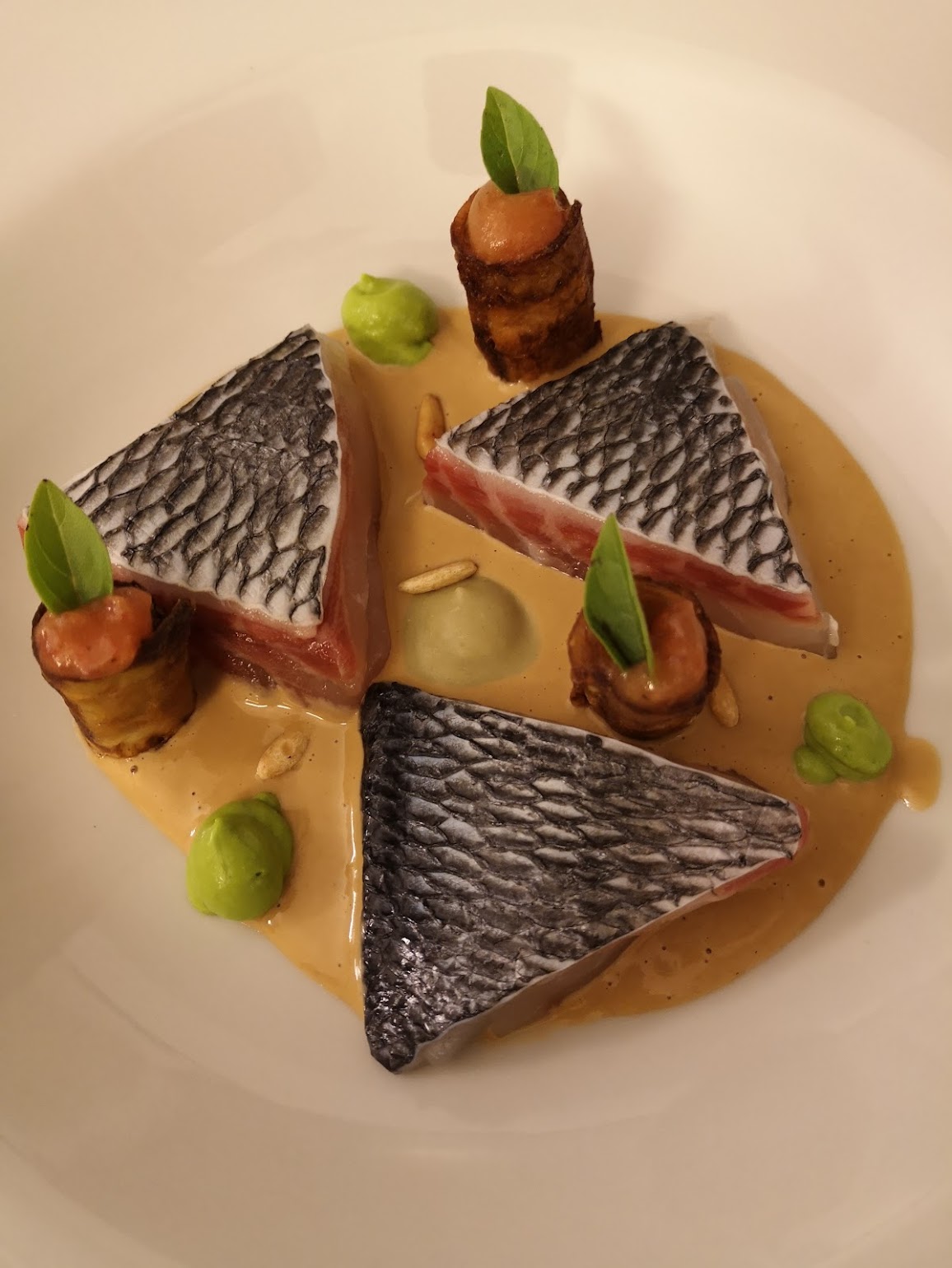 Filetti di ombrina, cannoli di melanzana ripieni di polpa di pomodoro, crema di piselli e salsa di pesce affumicato.
